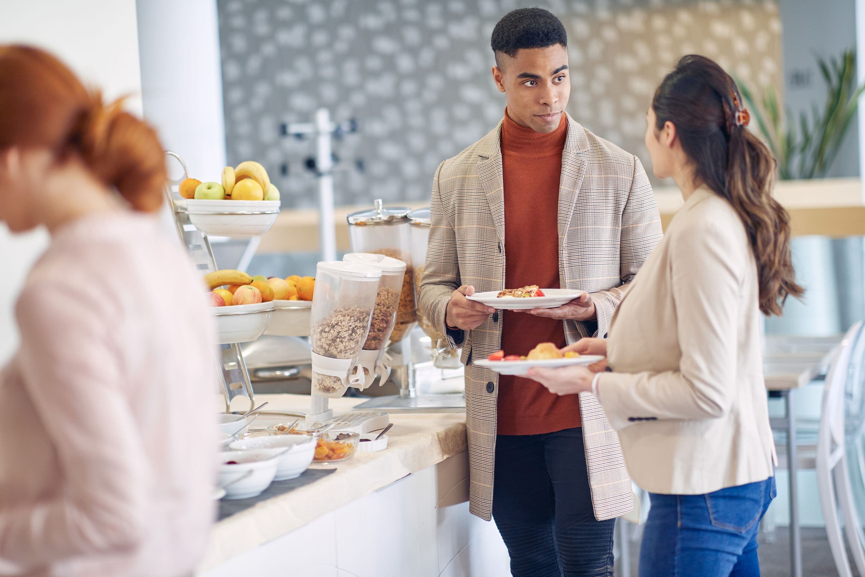 Colleagues chatting at breakfast food buffet.