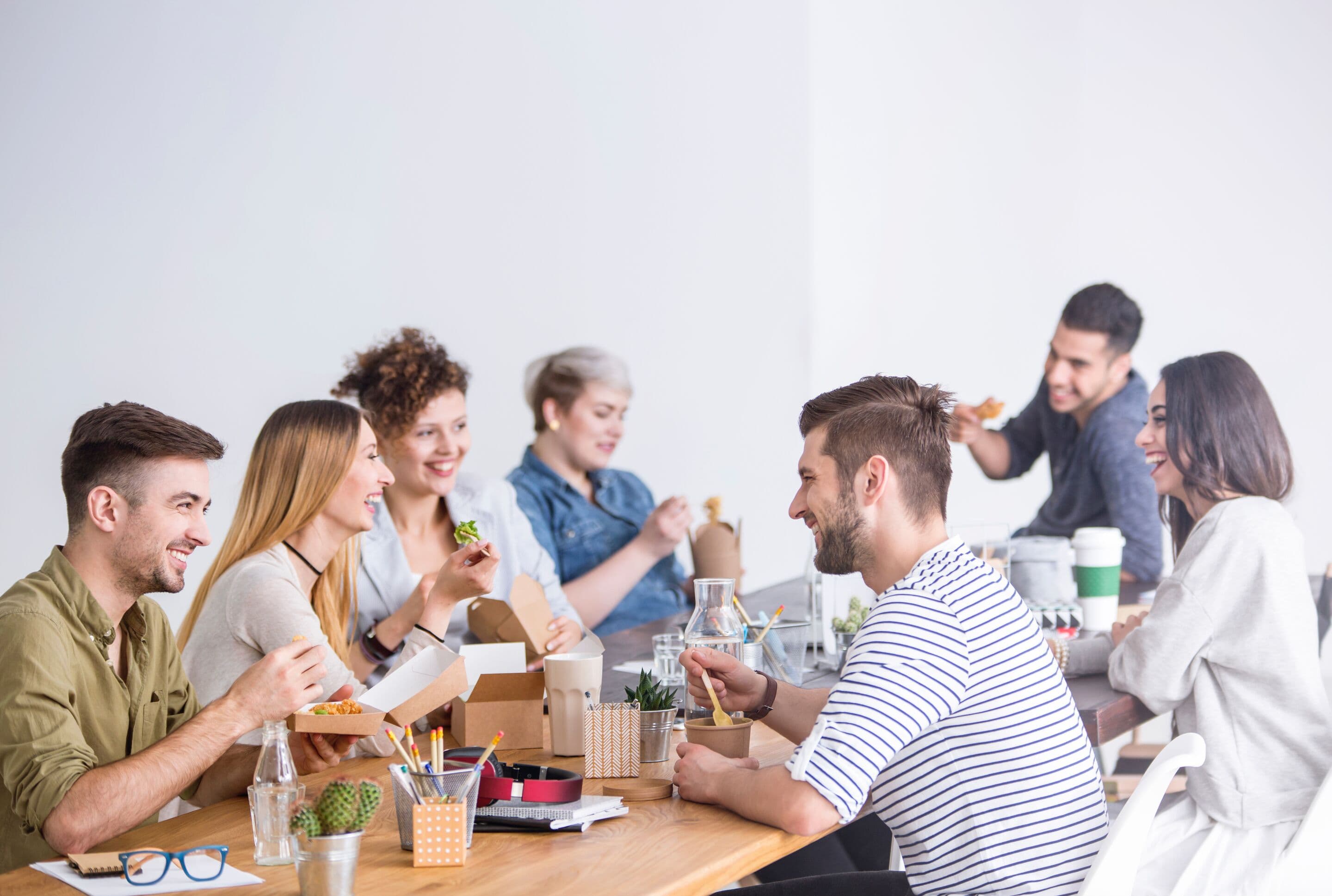Multicultural team of coworkers eating a healthy lunch together at the office